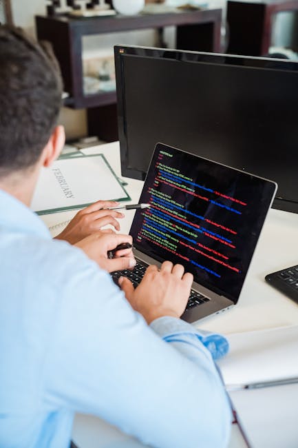 A close-up photograph of a computer screen displaying lines of code, featuring multicolored text including keywords, variables, and symbols typical of programming languages. The image is intentionally